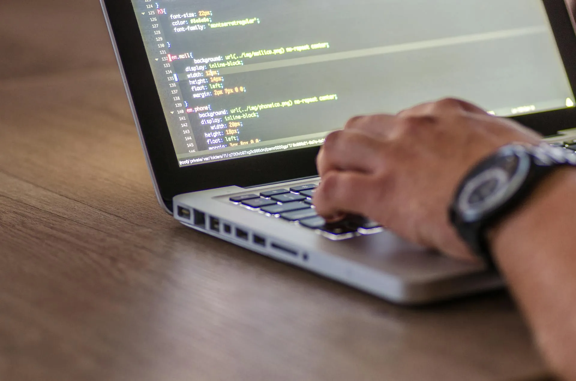 Developer working at a desk with two monitors displaying code